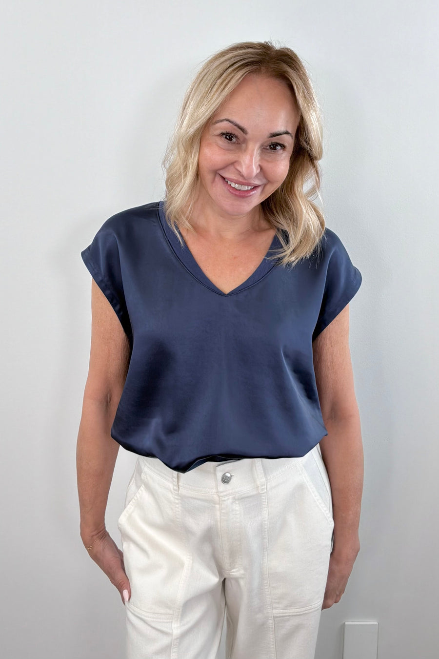 Woman wearing a navy satin V-neck short-sleeve top, front view