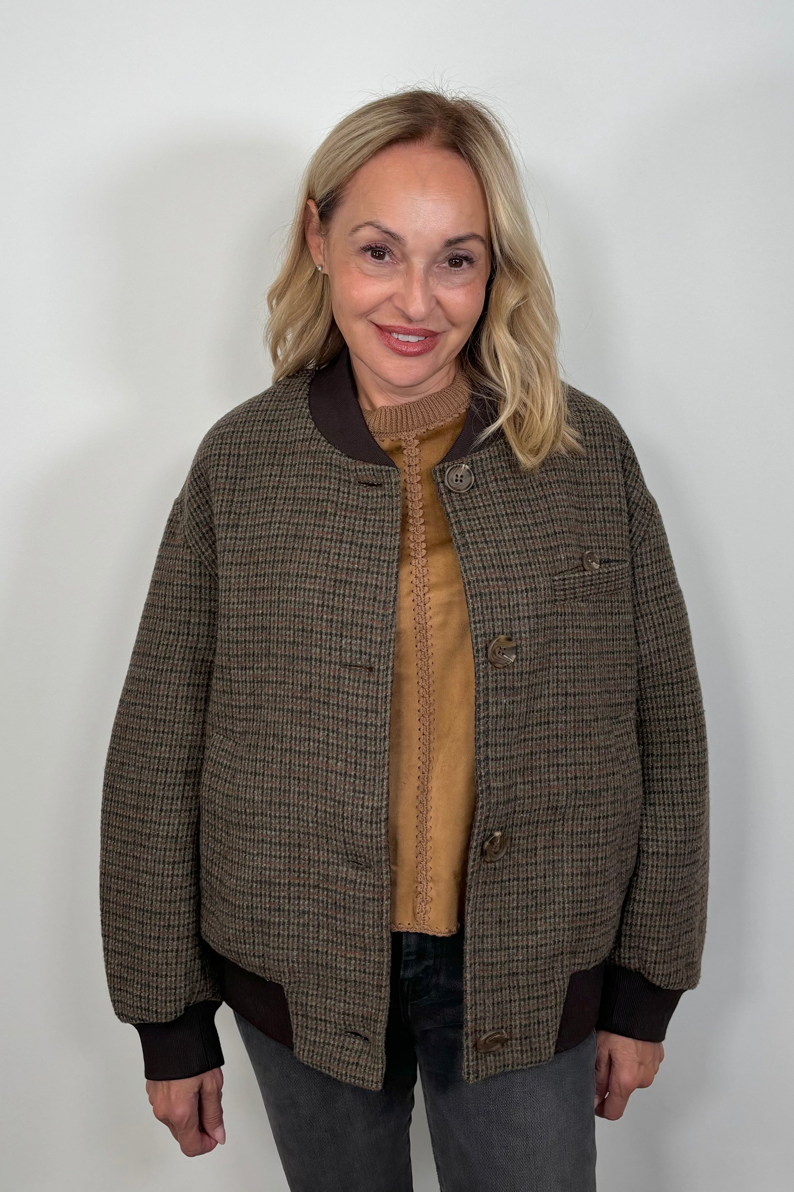 Woman wearing a green-brown plaid bomber jacket