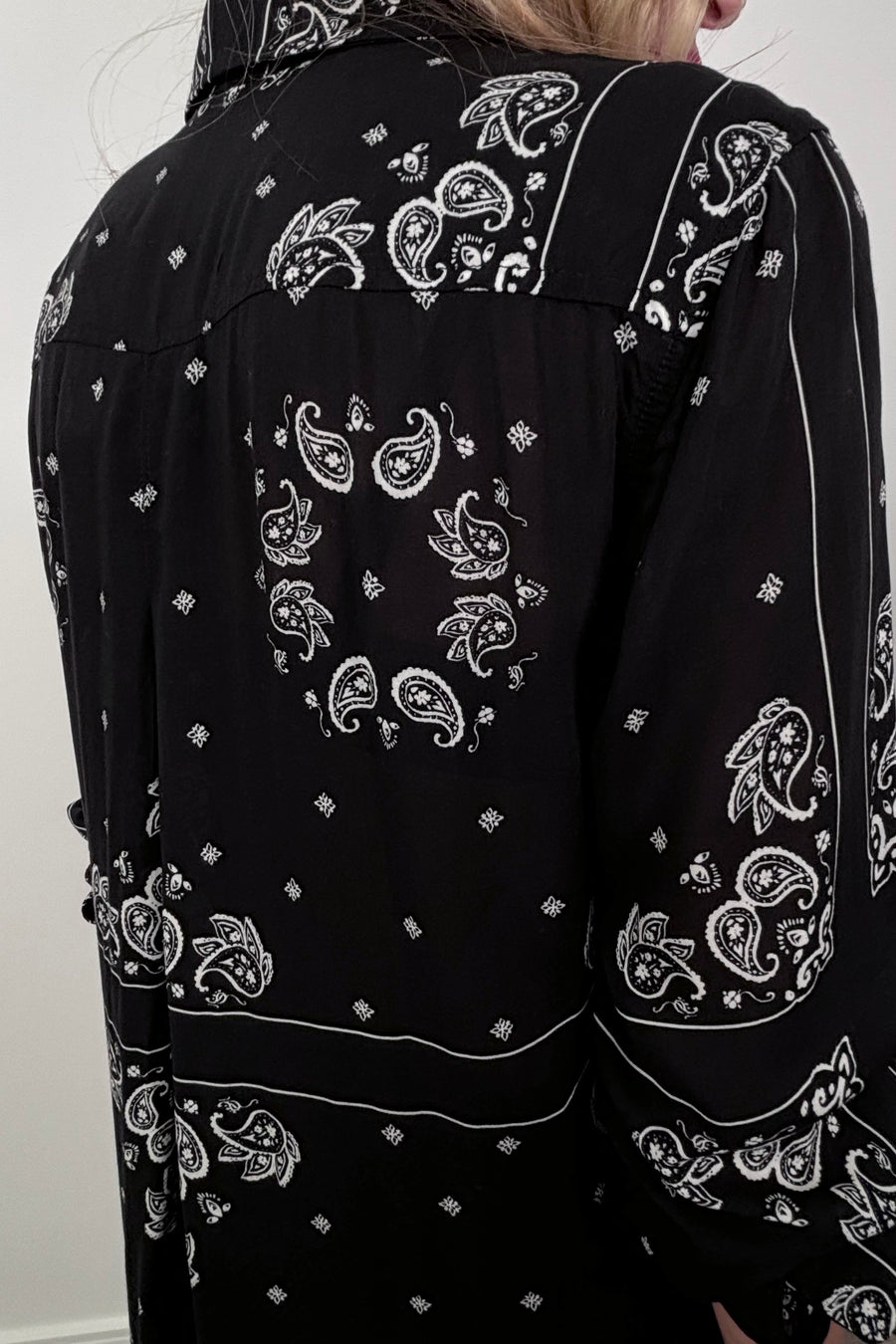 Back view of a woman wearing a bandana-patterned button down blouse