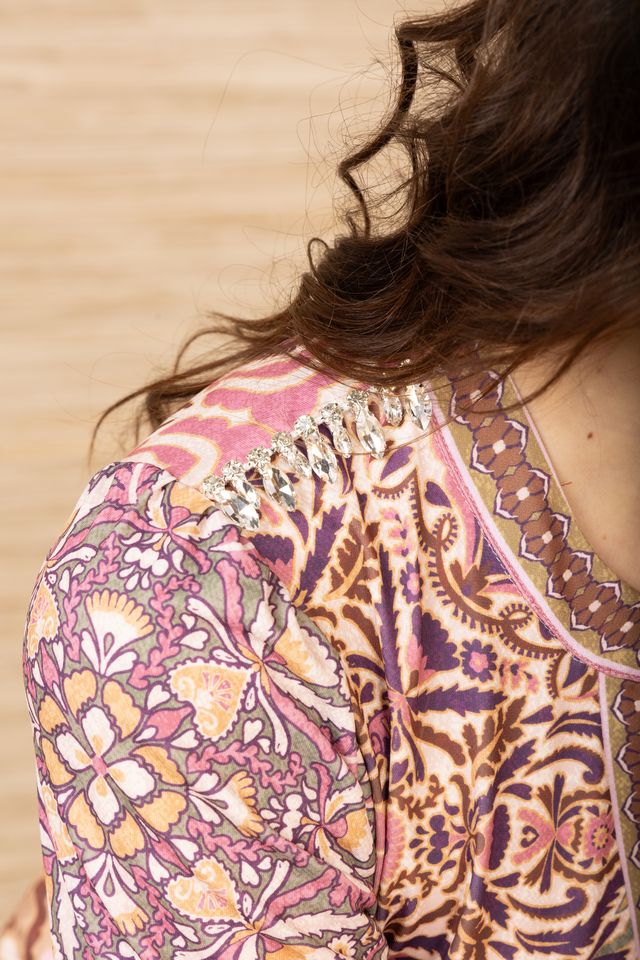 Close-up view of the shoulder of a woman wearing a short, cuffed sleeve, v-neck, patterned dress