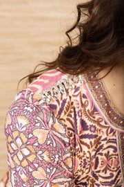 Close-up view of the shoulder of a woman wearing a short, cuffed sleeve, v-neck, patterned dress