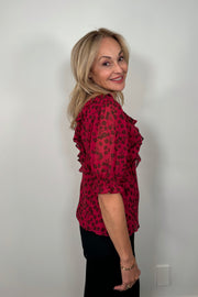 Side view of woman wearing a cool red chiffon top with a daisy pattern