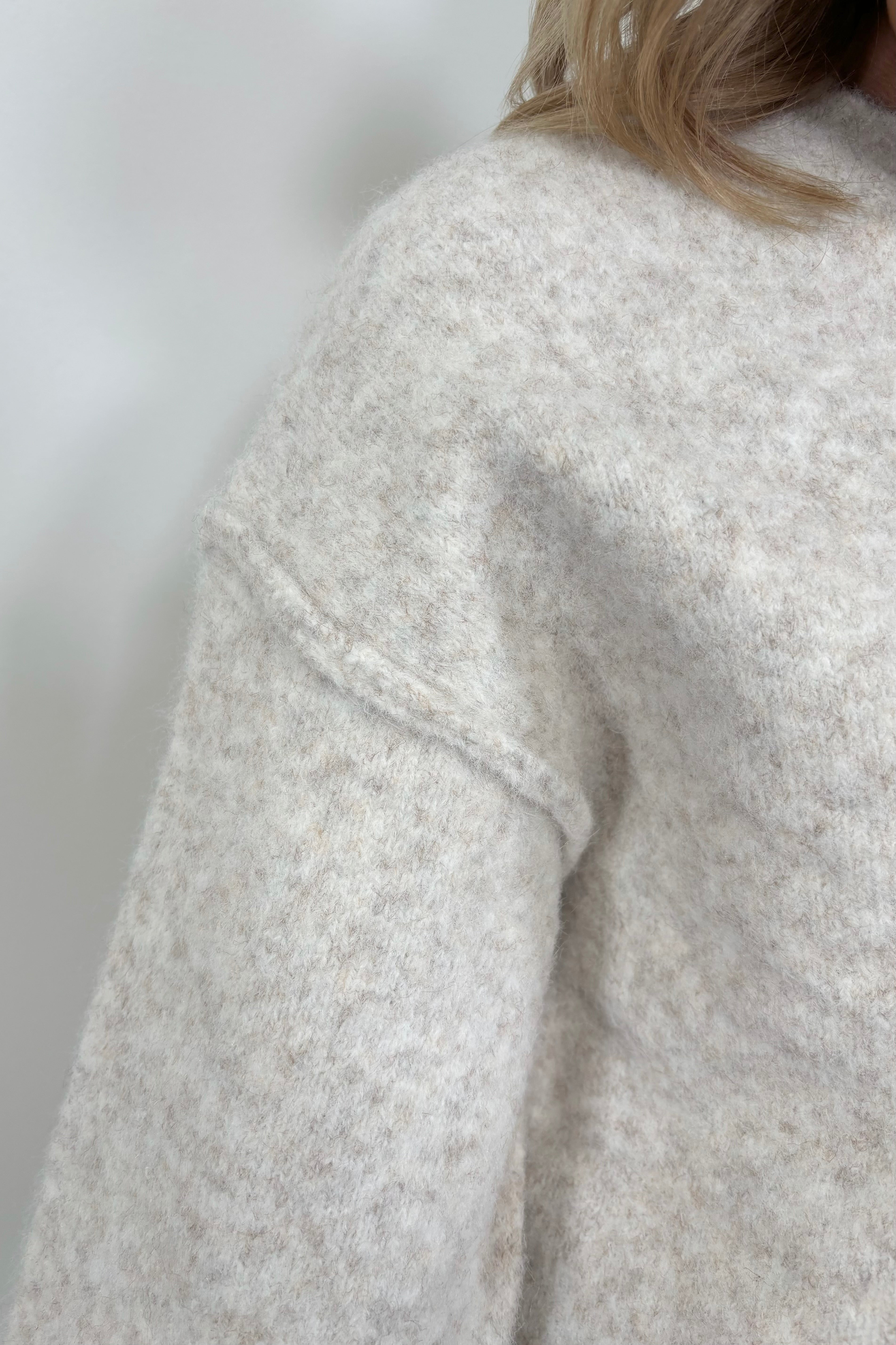 Close up of Front woman’s shoulder wearing an oatmeal coloured oversized knit sweater