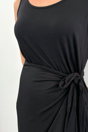 Close up of woman wearing a black midi dress with bow detailing n the side