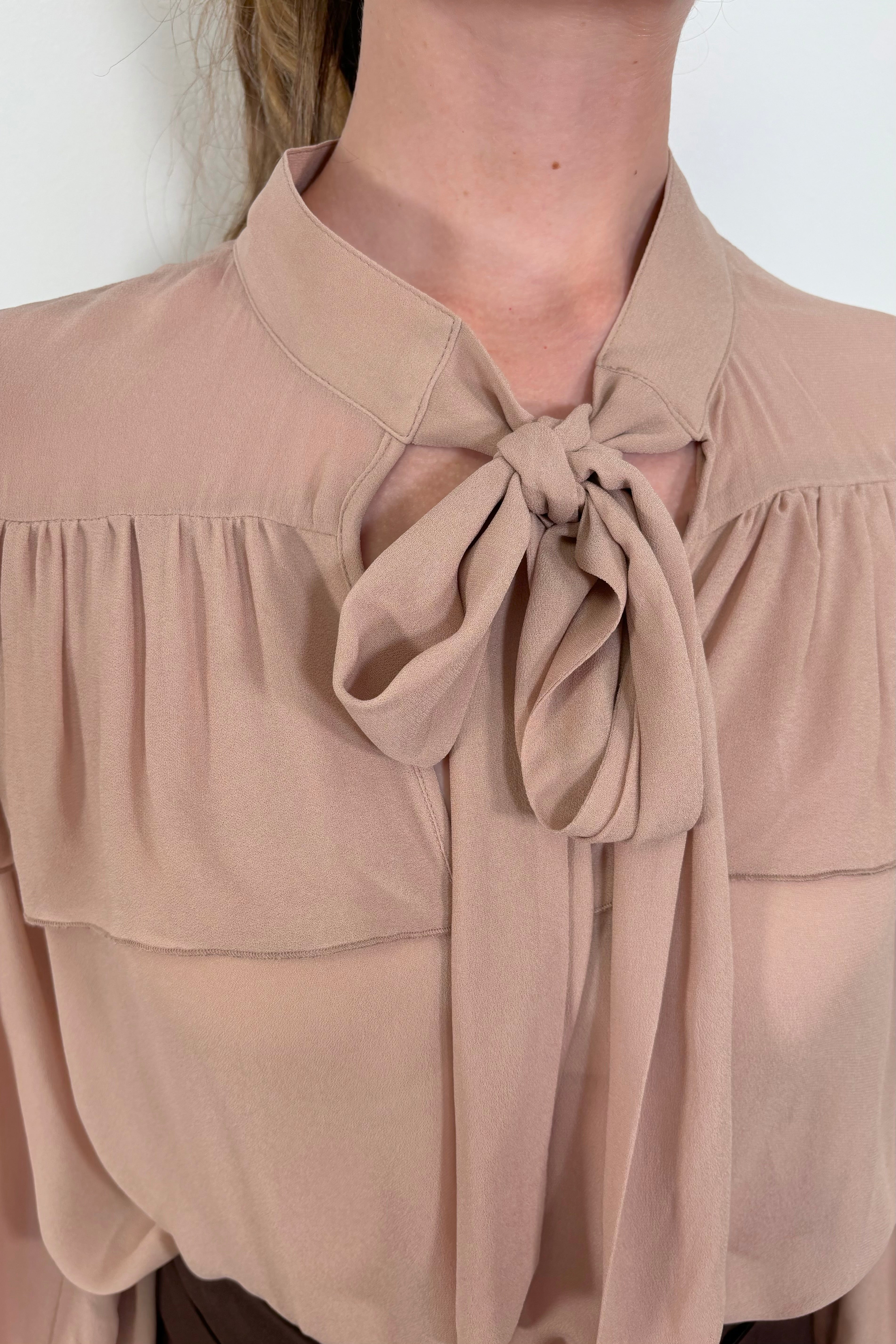 Close-up pf the tie neck of a nude coloured sheer ruffle blouse