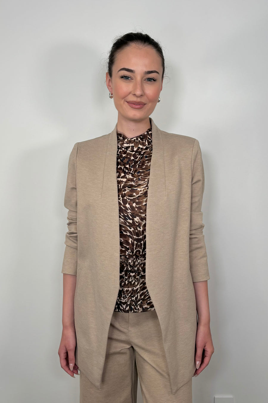 Front view of woman using a beige neutral stretch collarless ponte blazer