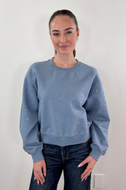 Woman wearing blue pullover with rhinestone details all over
