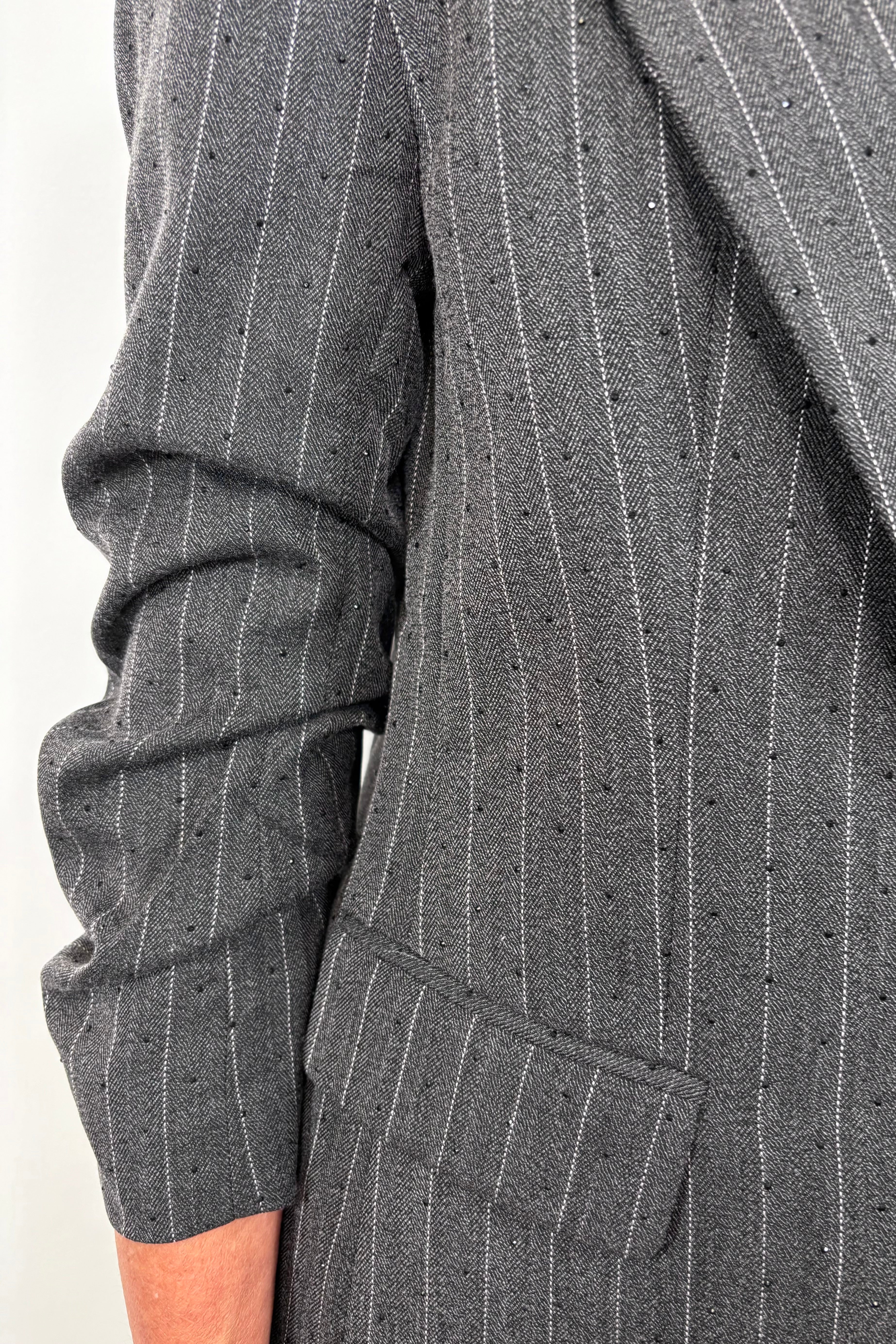 Close up of the scrunched sleeve of a pinstriped gray blazer with sparkles