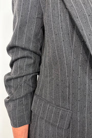 Close up of the scrunched sleeve of a pinstriped gray blazer with sparkles