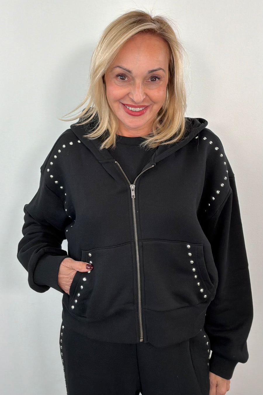 woman wearing a black zip-up with studs along the seems