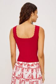 Woman wearing a knit red tank top with scallop trim 