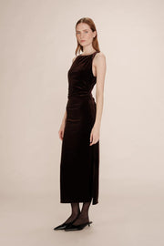 Woman wearing a brown velvet dress against a beige background