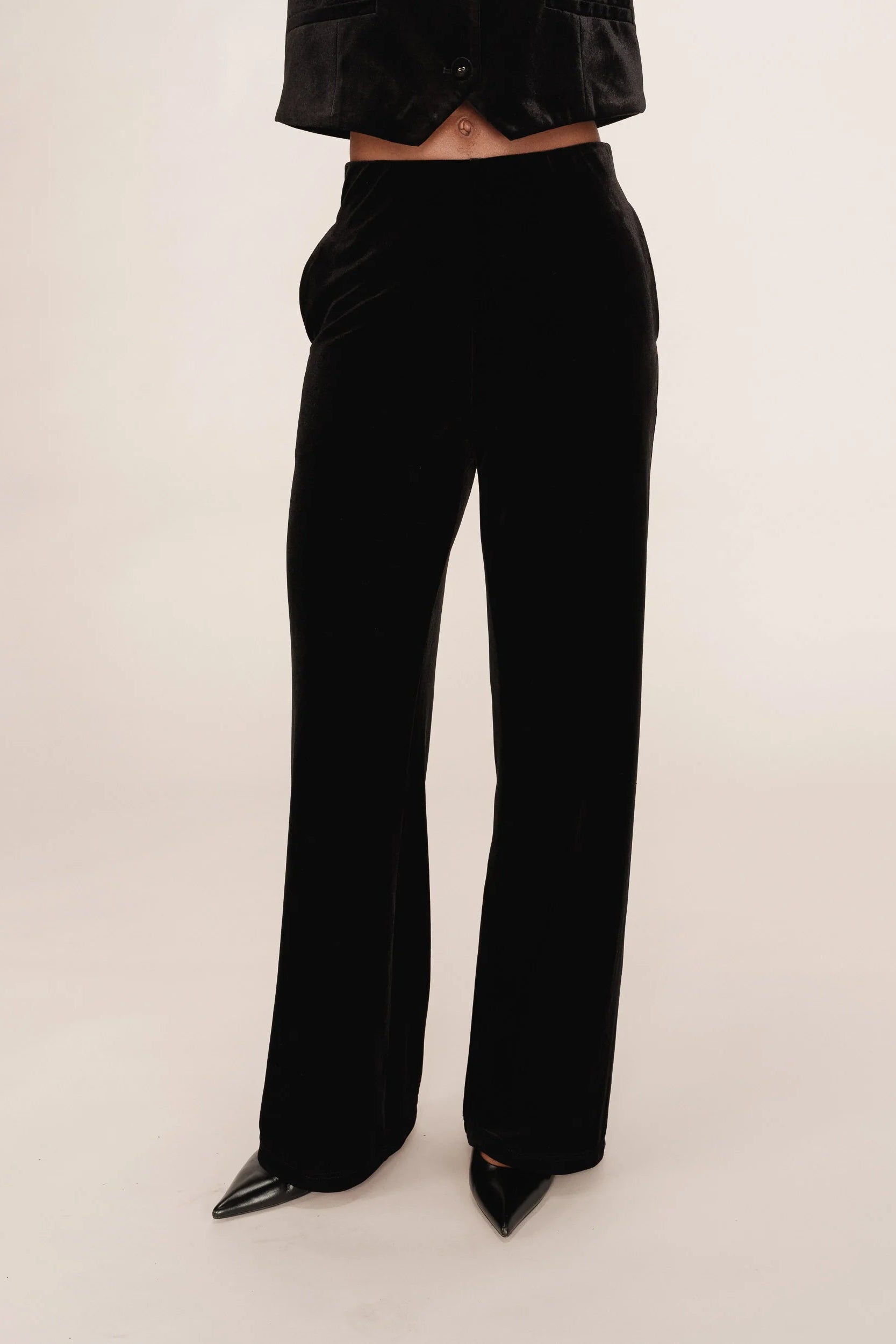 Black velvet pants worn by a person on a white background