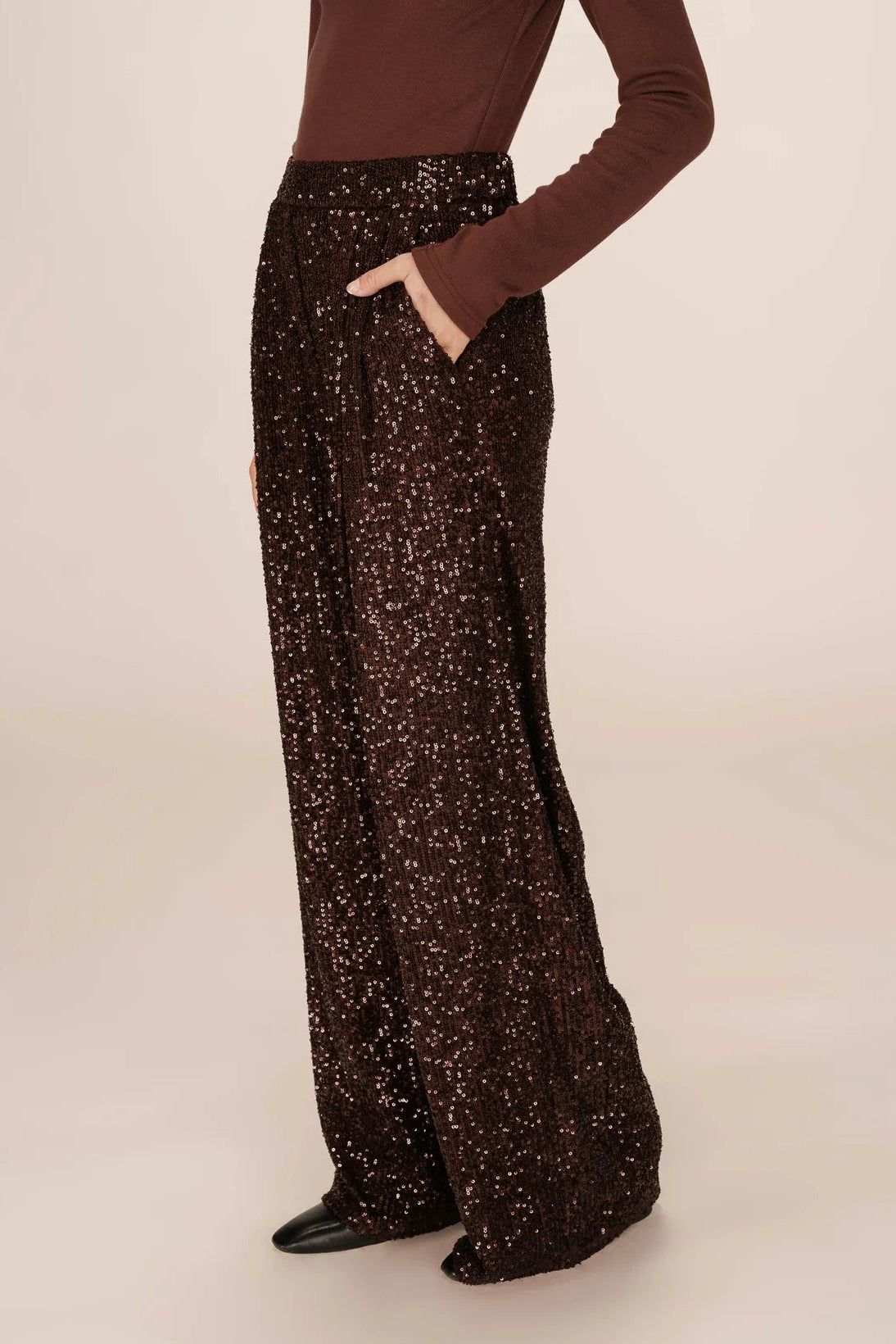 Person wearing brown sequin pants on a beige background