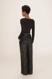 person wearing black long sleeve top and black wide leg sequin pants