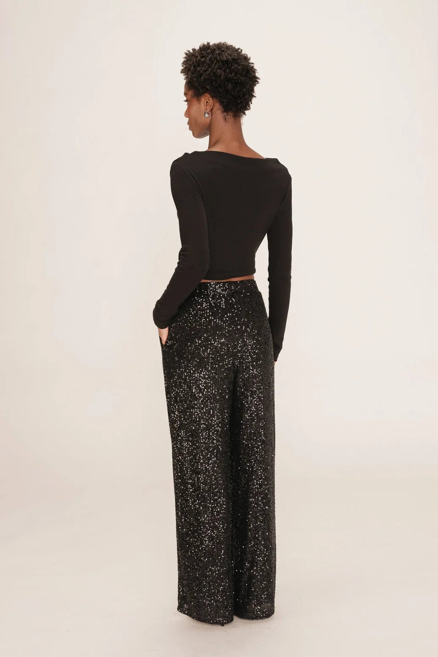 person wearing black long sleeve top and black wide leg sequin pants