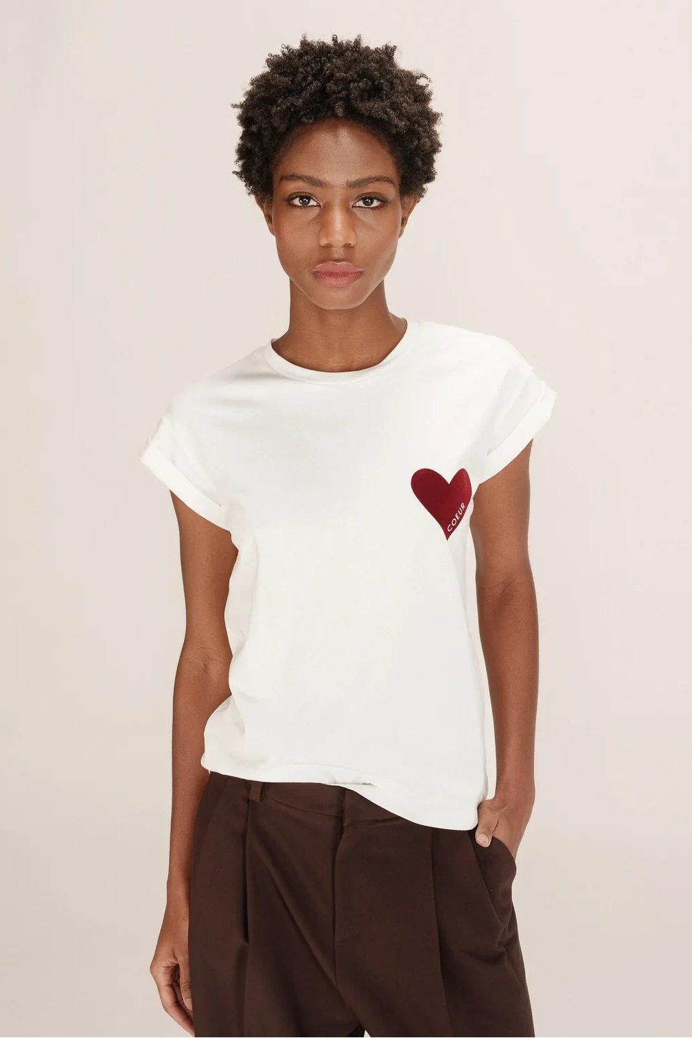 Person wearing a white t-shirt with a red heart design on a plain background