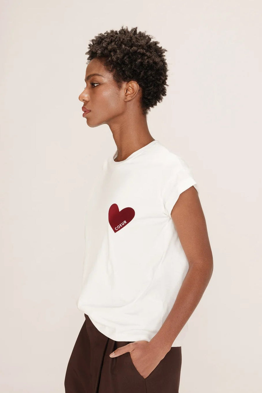 Person wearing a white t-shirt with a red heart design on a plain background