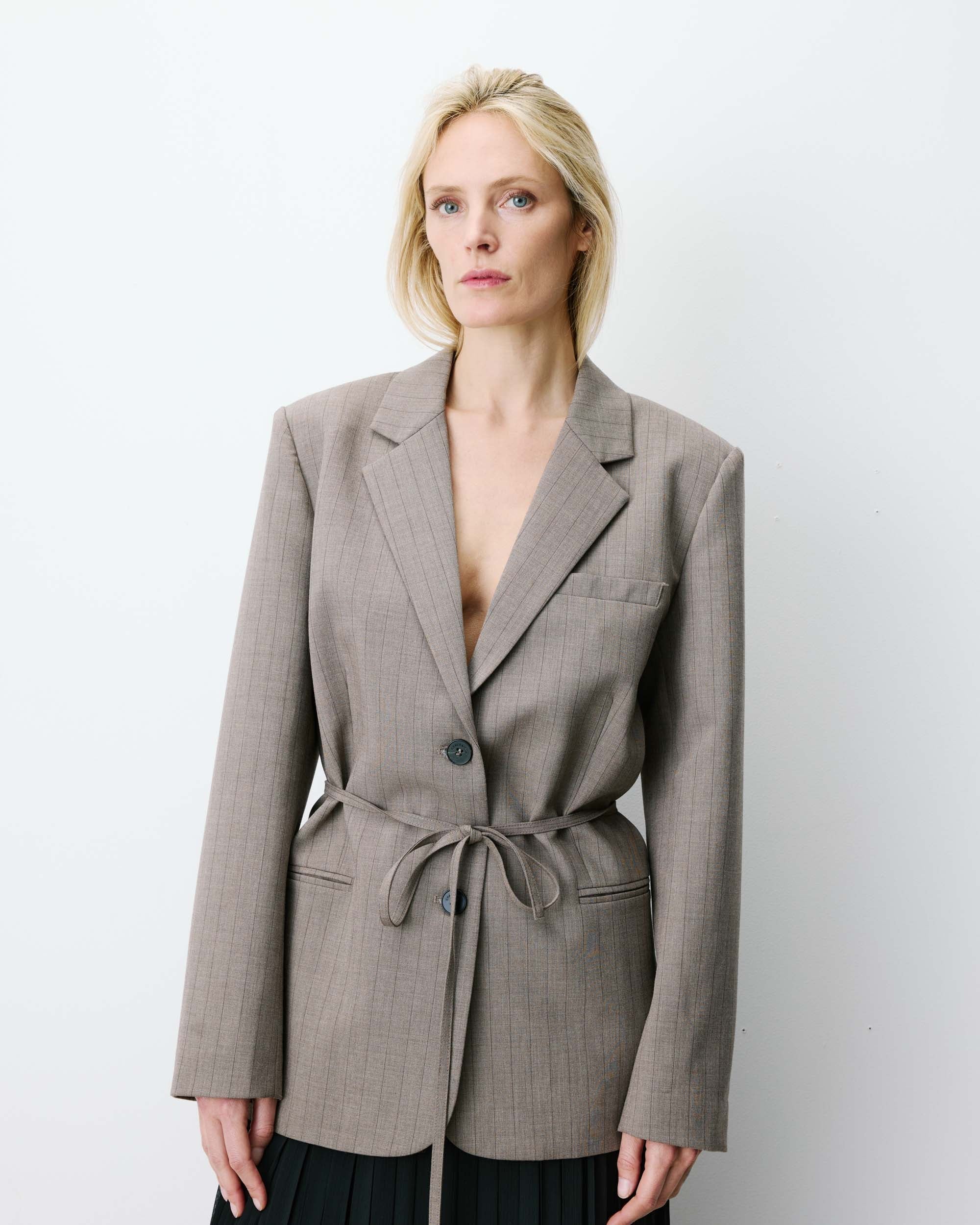 Woman wearing a gray blazer with a belt