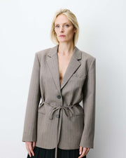 Woman wearing a gray blazer with a belt