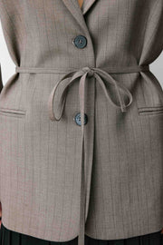 Woman wearing a gray blazer with a belt