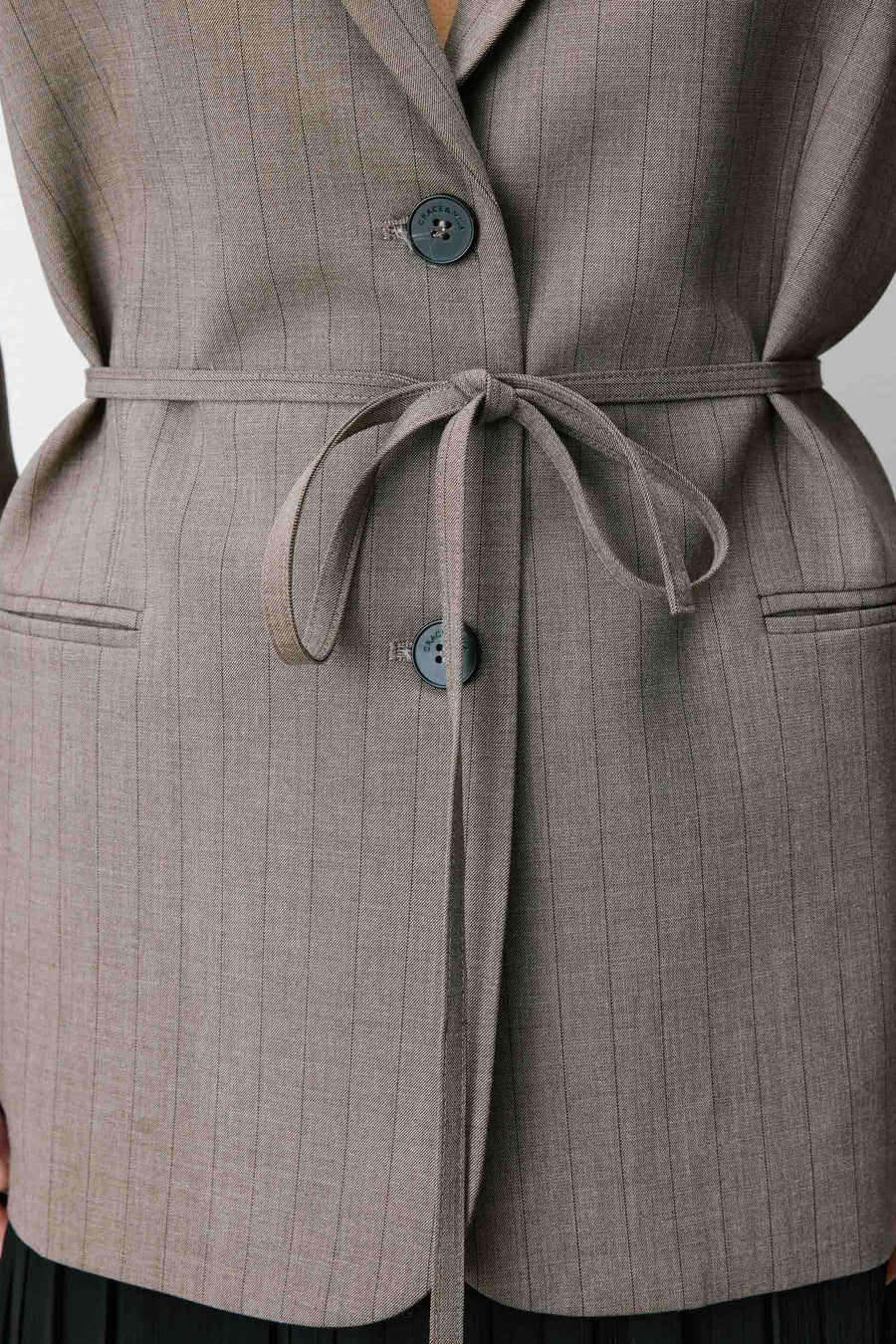 Woman wearing a gray blazer with a belt