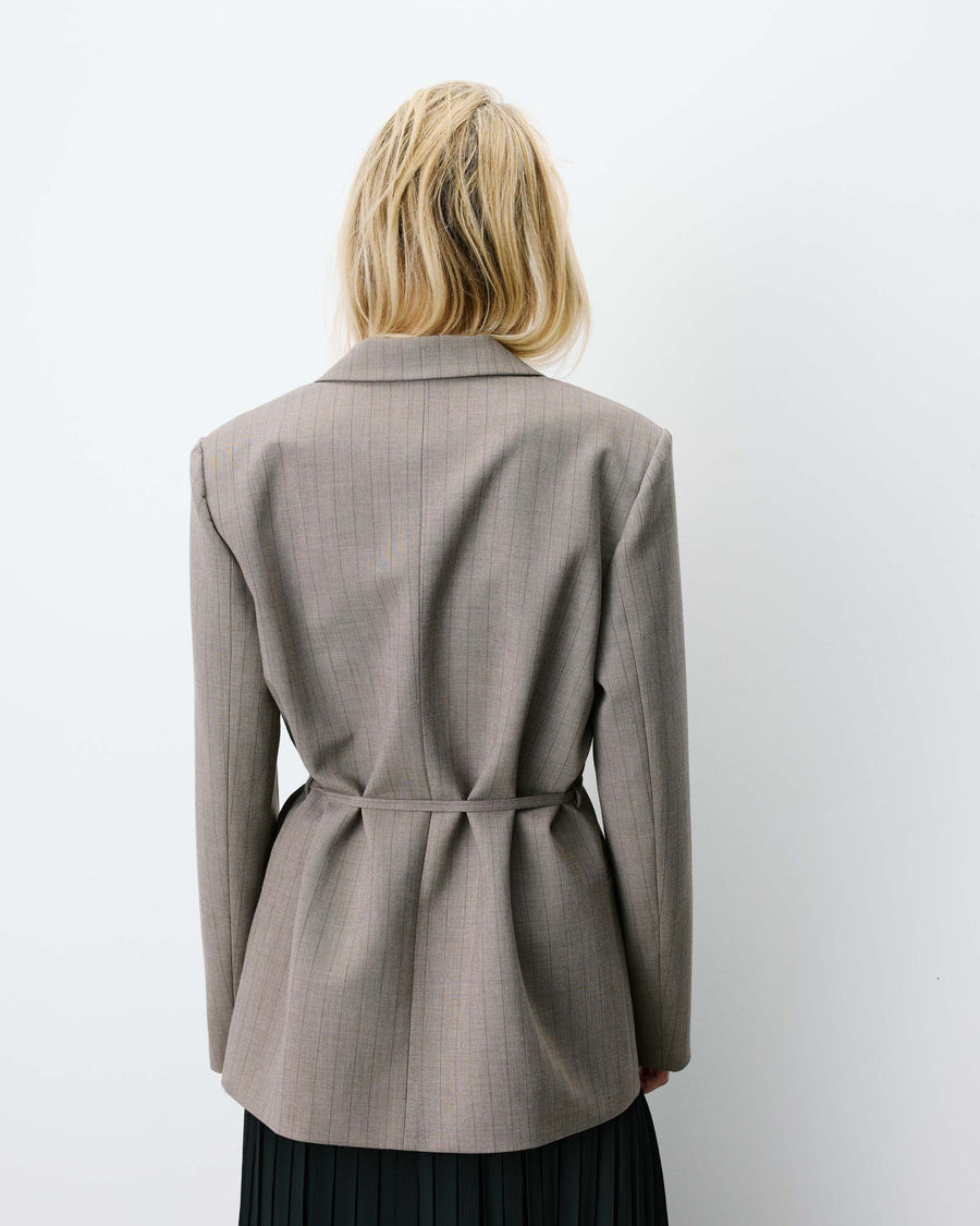 Woman wearing a gray blazer with a belt