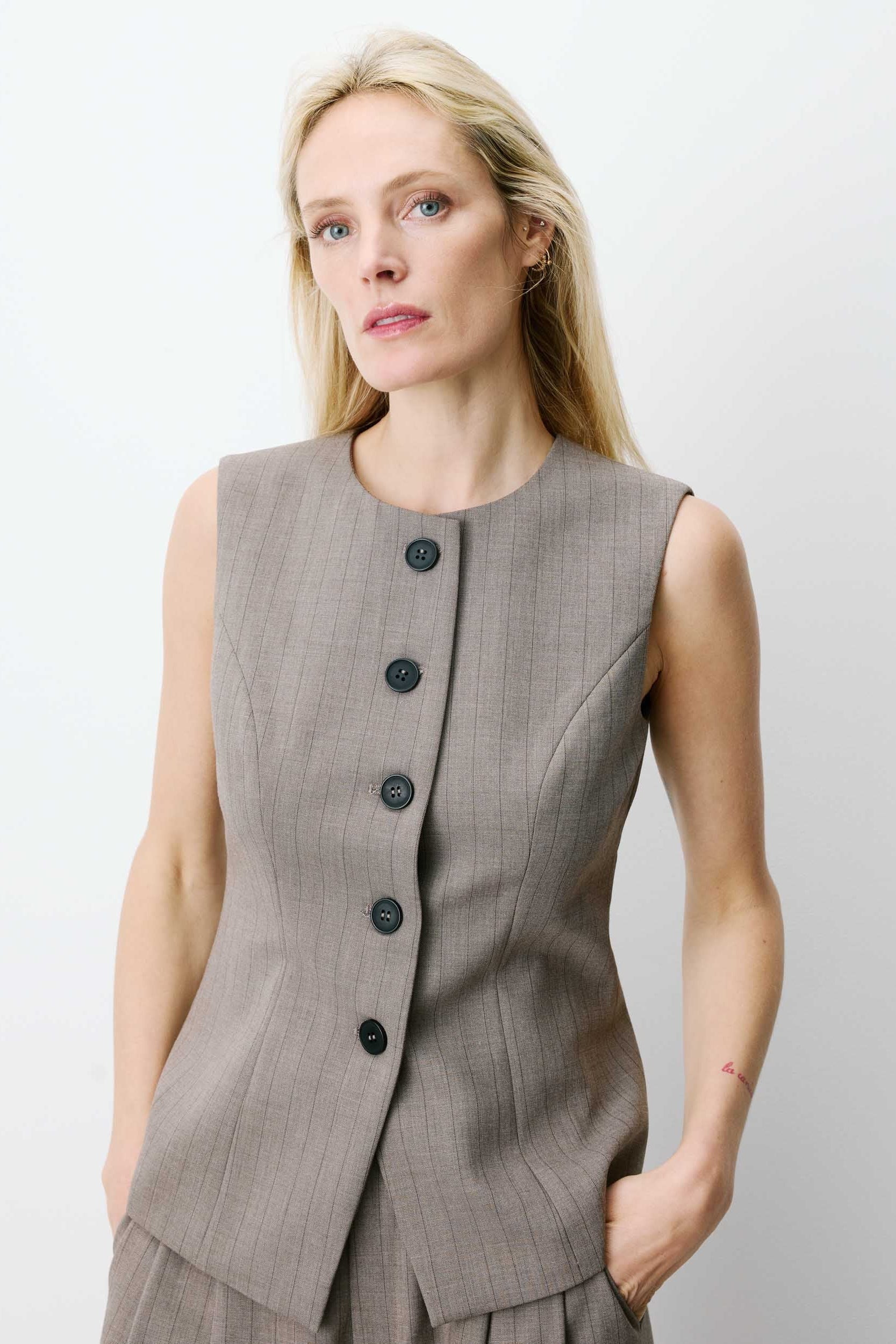 Woman wearing a sleeveless gray vest with buttons