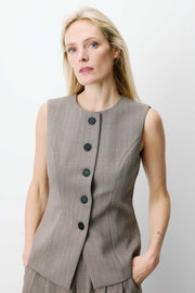 Woman wearing a sleeveless gray vest with buttons