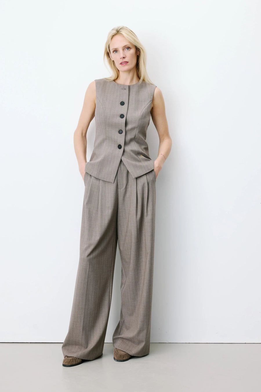 Woman wearing a sleeveless gray vest with buttons