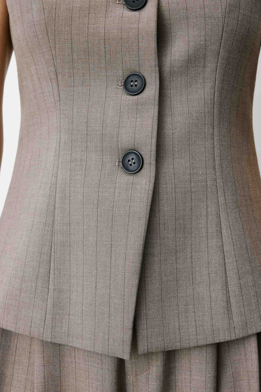 Woman wearing a sleeveless gray vest with buttons