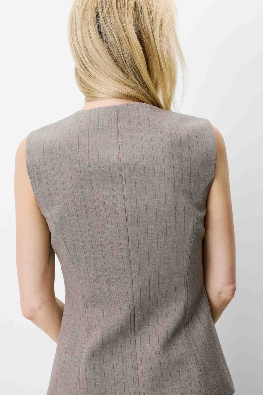 Woman wearing a sleeveless gray vest with buttons
