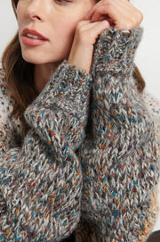 Close up of woman wearing a light gray, beige and dark gray knitted cardigan