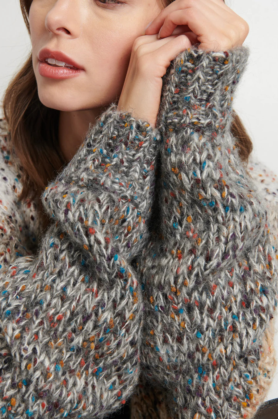 Close up of woman wearing a light gray, beige and dark gray knitted cardigan