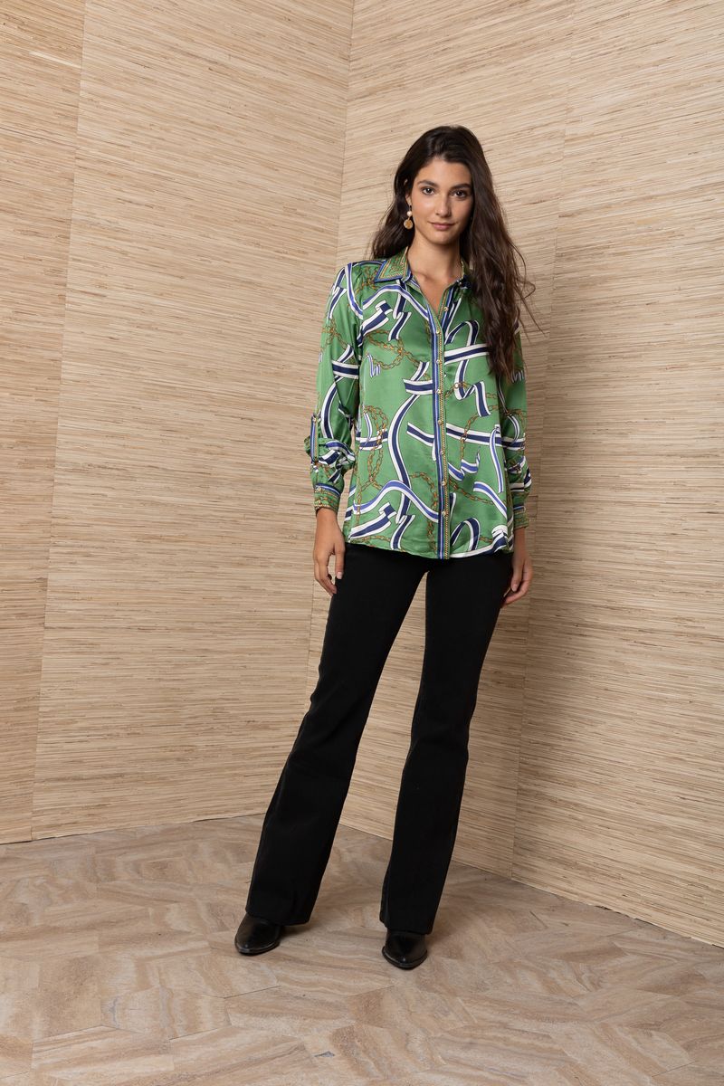 A woman modeling a green silk button-up shirt with an abstract blue, white, and gold chain pattern.