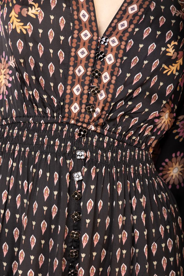 Close-up view of woman wearing a black, pink and brown patterned long sleeve midi dress