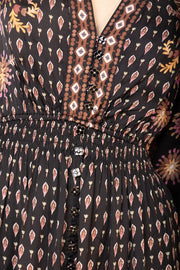 Close-up view of woman wearing a black, pink and brown patterned long sleeve midi dress