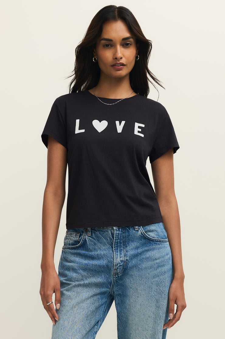 Woman wearing wearing a black crewneck t-shirt with the word "LOVE" written on the front in white lettering, front view