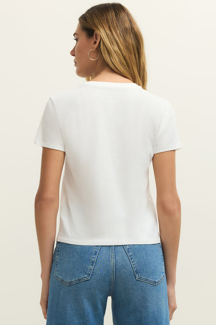 Woman wearing a white short sleeve graphic tee with the words "La Dolce Vita The Sweet Life" on the front and a picture of lemons, back view