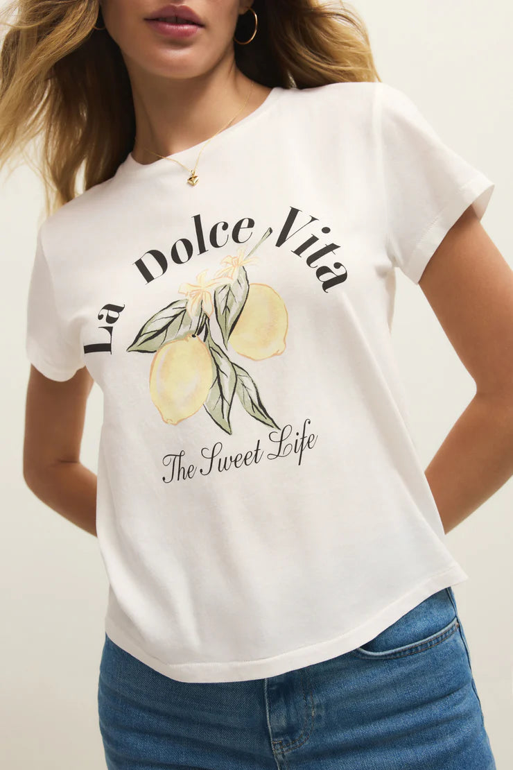 Woman wearing a white short sleeve graphic tee with the words "La Dolce Vita The Sweet Life" on the front and a picture of lemons, detail view