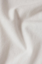 Woman wearing a white short sleeve graphic tee with the words "La Dolce Vita The Sweet Life" on the front and a picture of lemons, closeup view