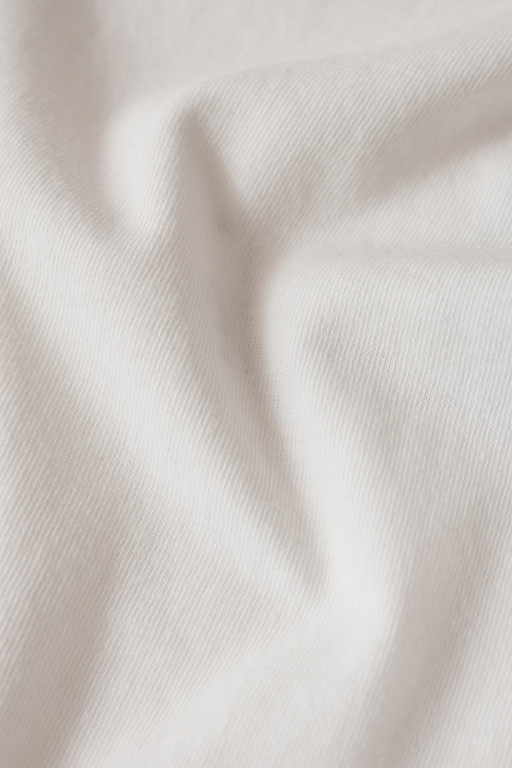 Woman wearing a white short sleeve graphic tee with the words "La Dolce Vita The Sweet Life" on the front and a picture of lemons, closeup view