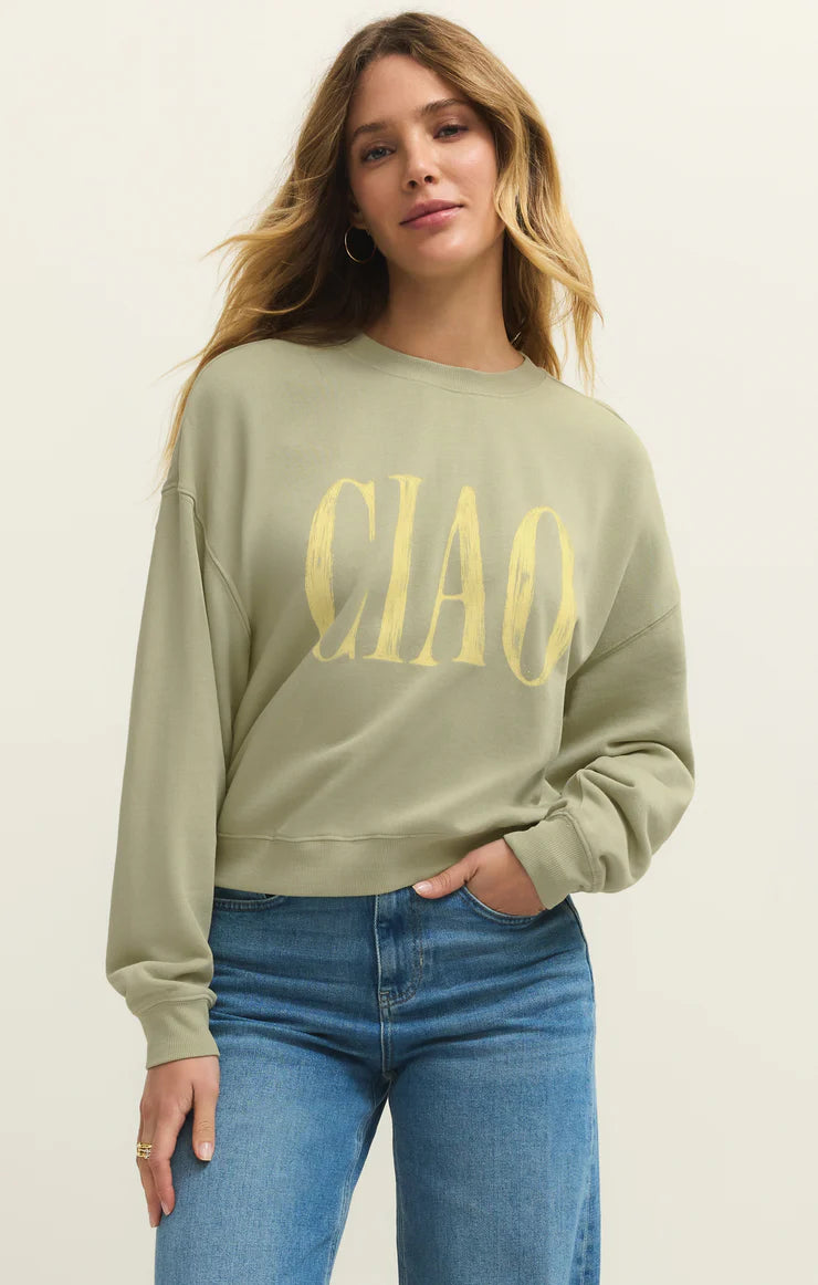Woman wearing a sage green long sleeve sweatshirt with the word "Ciao" written on the front in yellow front view