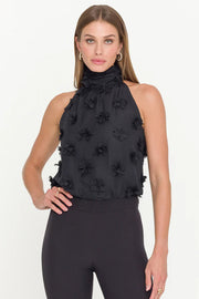 woman wearing a halterneck black top with 3D fabric flowers all over