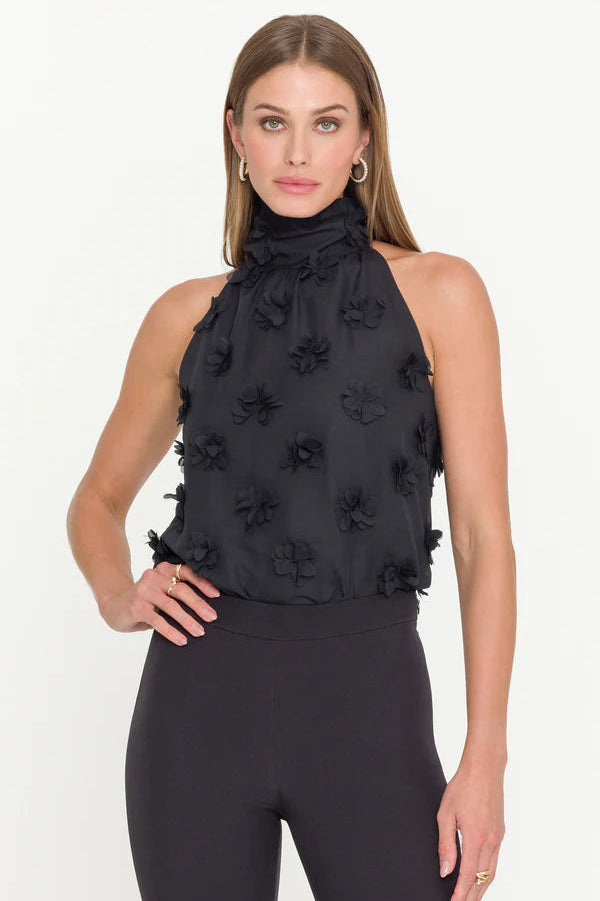 woman wearing a halterneck black top with 3D fabric flowers all over