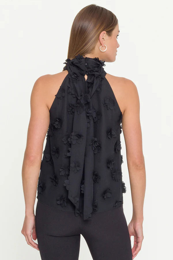 woman wearing  a halterneck black top with 3D fabric flowers all over