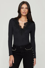 Woman wearing a black long-sleeve top with lace details in the v-neck