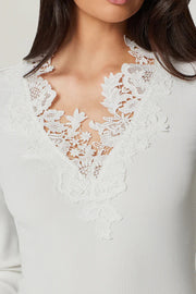 Woman wearing a white blouse with lace details and black pants