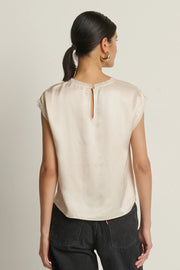 woman wearing a cream satin cap sleeved top