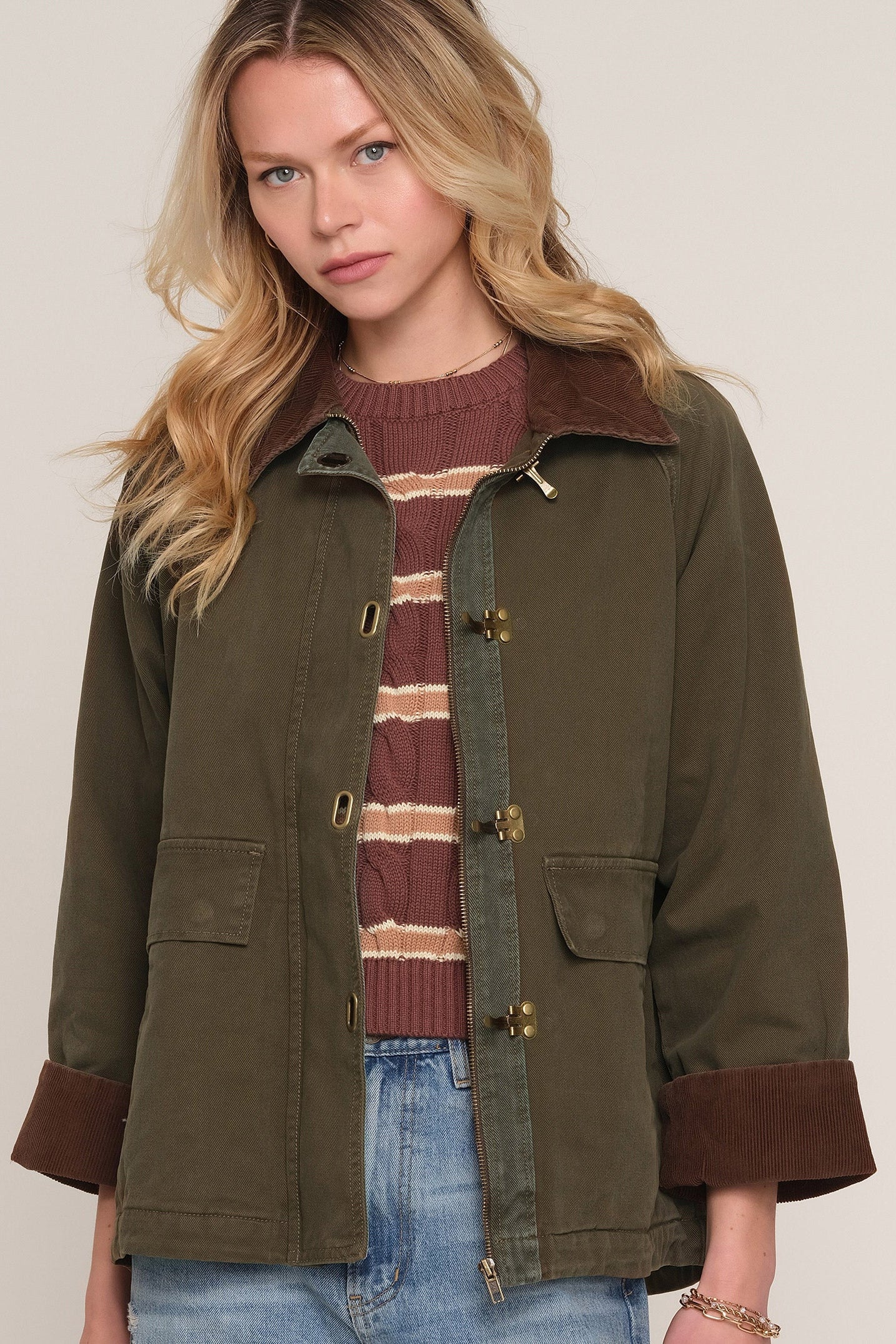 A woman wearing an olive green utility jacket with brown corduroy collar and cuffs, 